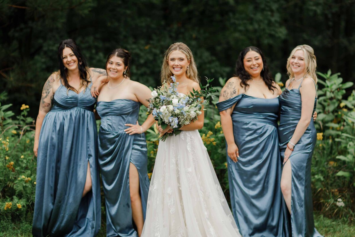 Bridesmaids and bride in matching blue dresses at an outdoor wedding.