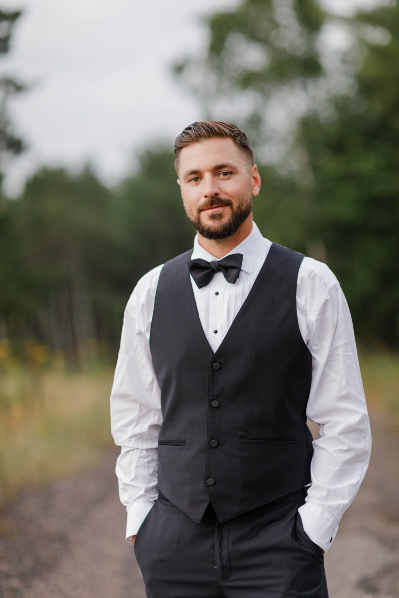 Groom in tuxedo at lakeside wedding in Wisconsin, outdoors.