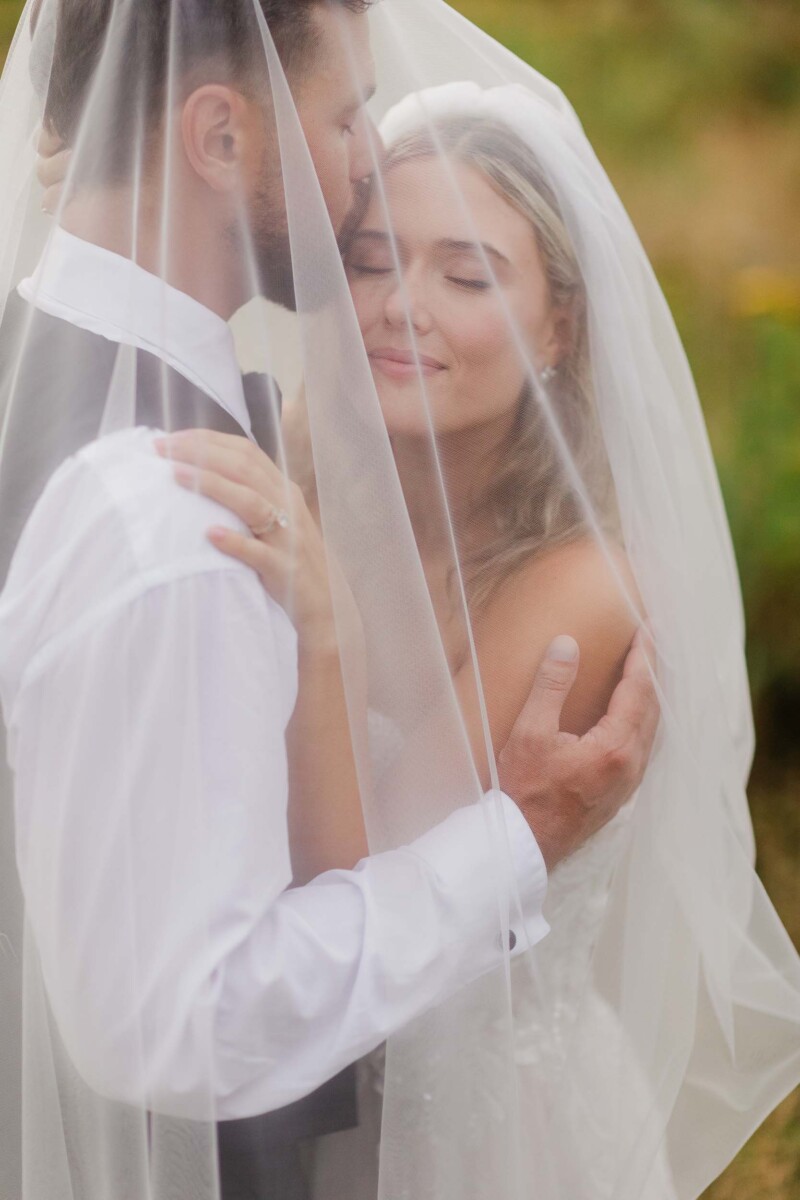 Bride and groom sharing intimate moment behind wedding veil.