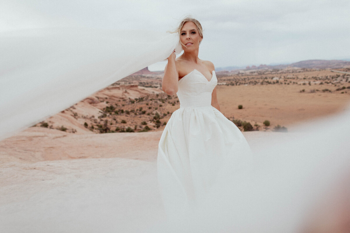 Bride in wedding dress at Moab Utah with desert landscape background.