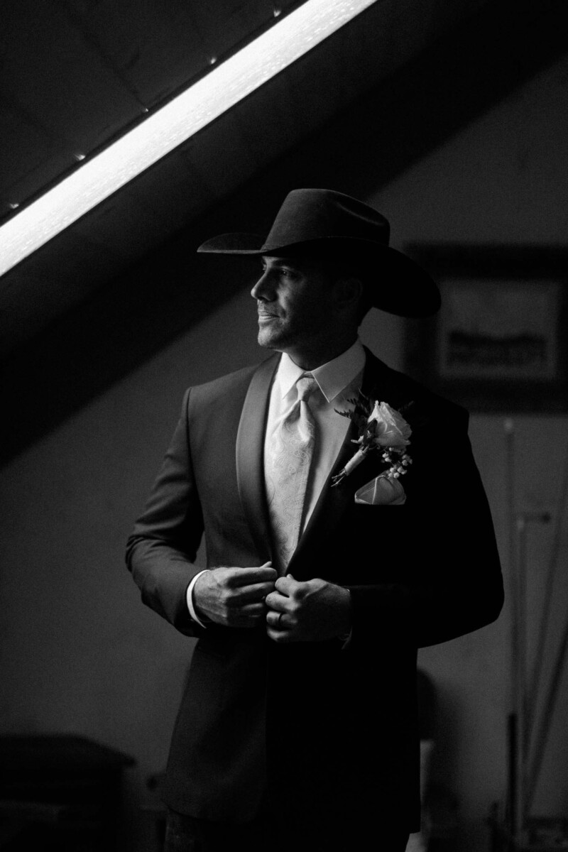Groom in a suit and cowboy hat, preparing for his Utah fall wedding.