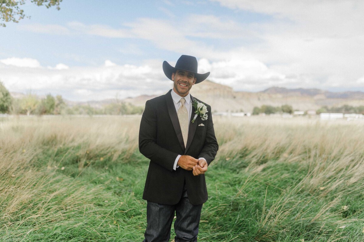 Sean smiling in a black suit and cowboy hat outdoors.