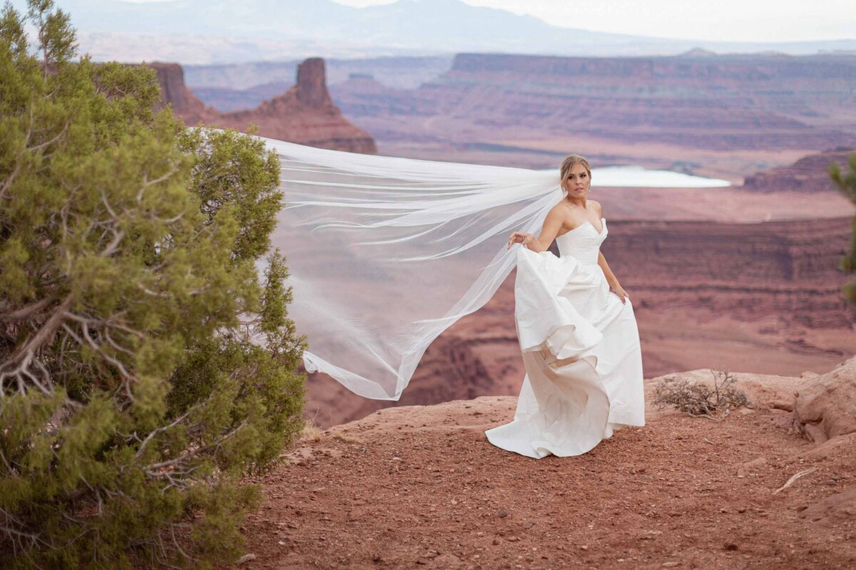 Bride in wedding dress with veil at Moab Utah canyon.