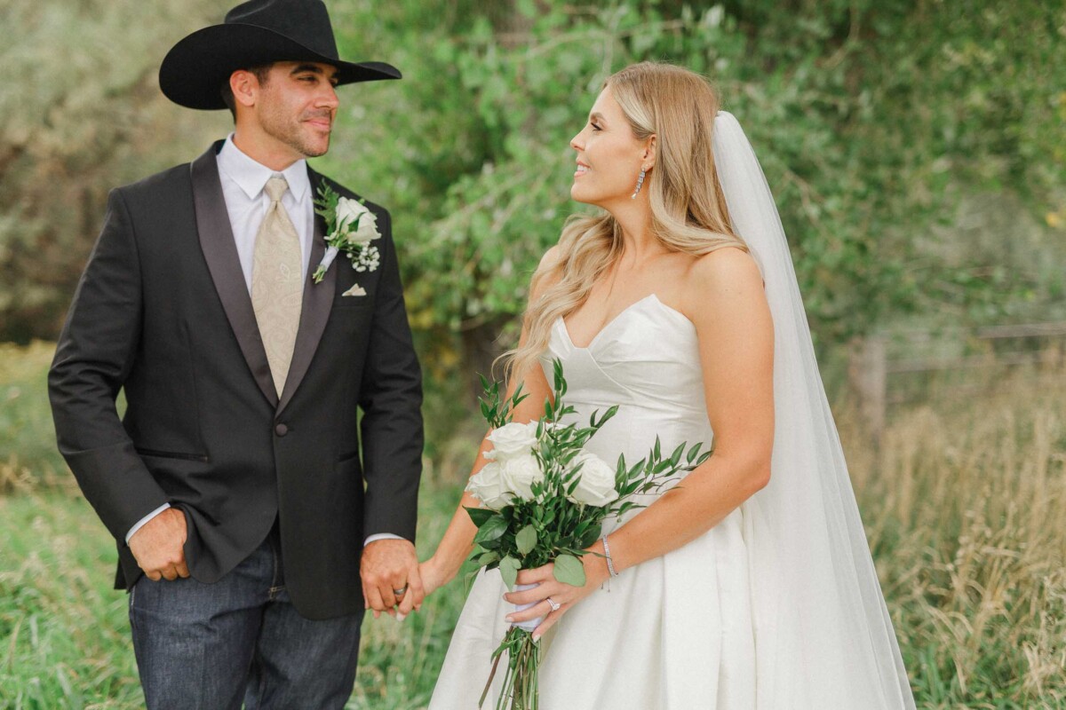 Bride and groom holding hands outdoors during fall wedding.