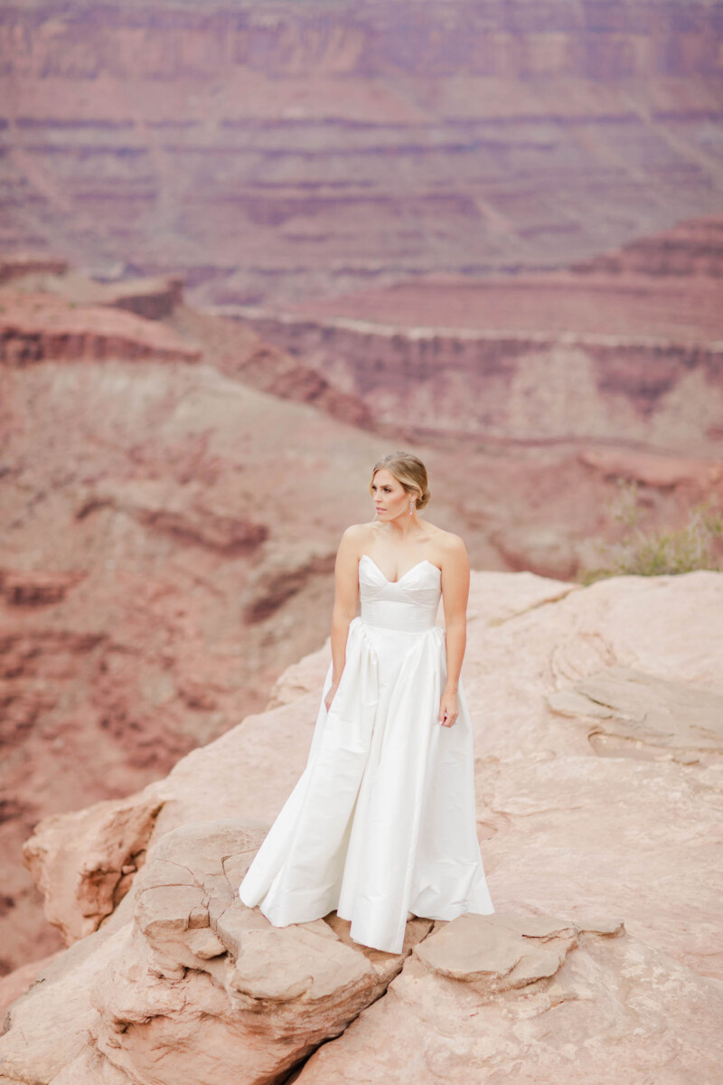 Bride standing on canyon edge in Moab Utah.