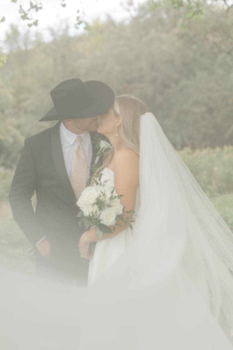 Elegant couple sharing a kiss outdoors during fall wedding in Utah.