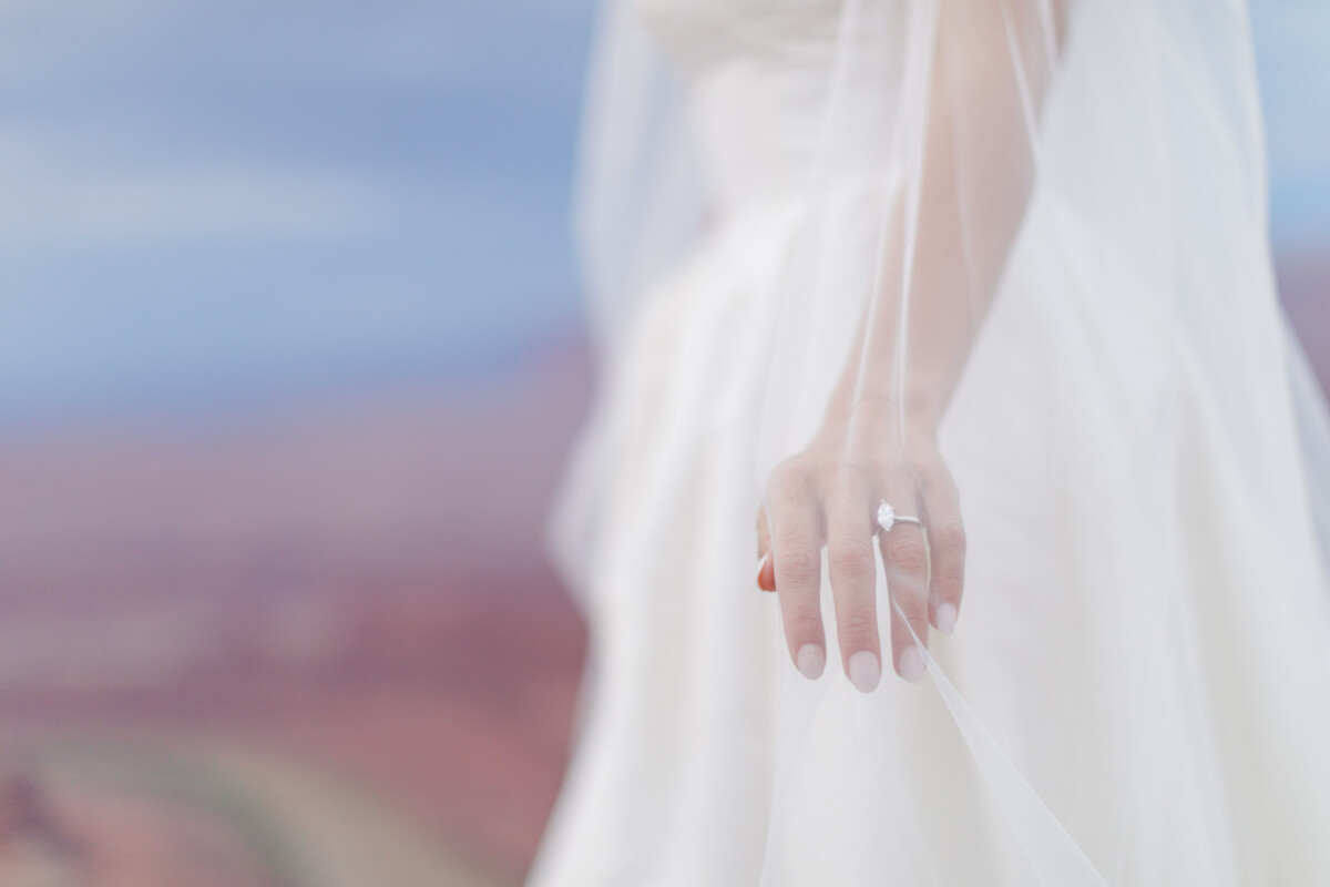 Bride's hand with wedding ring in Moab Utah landscape.