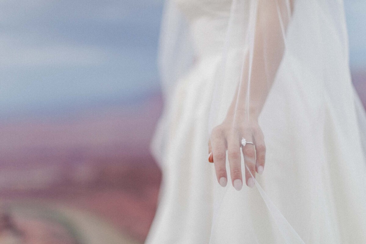 Bride's hand with engagement ring, soft focus, Moab Utah landscape background.