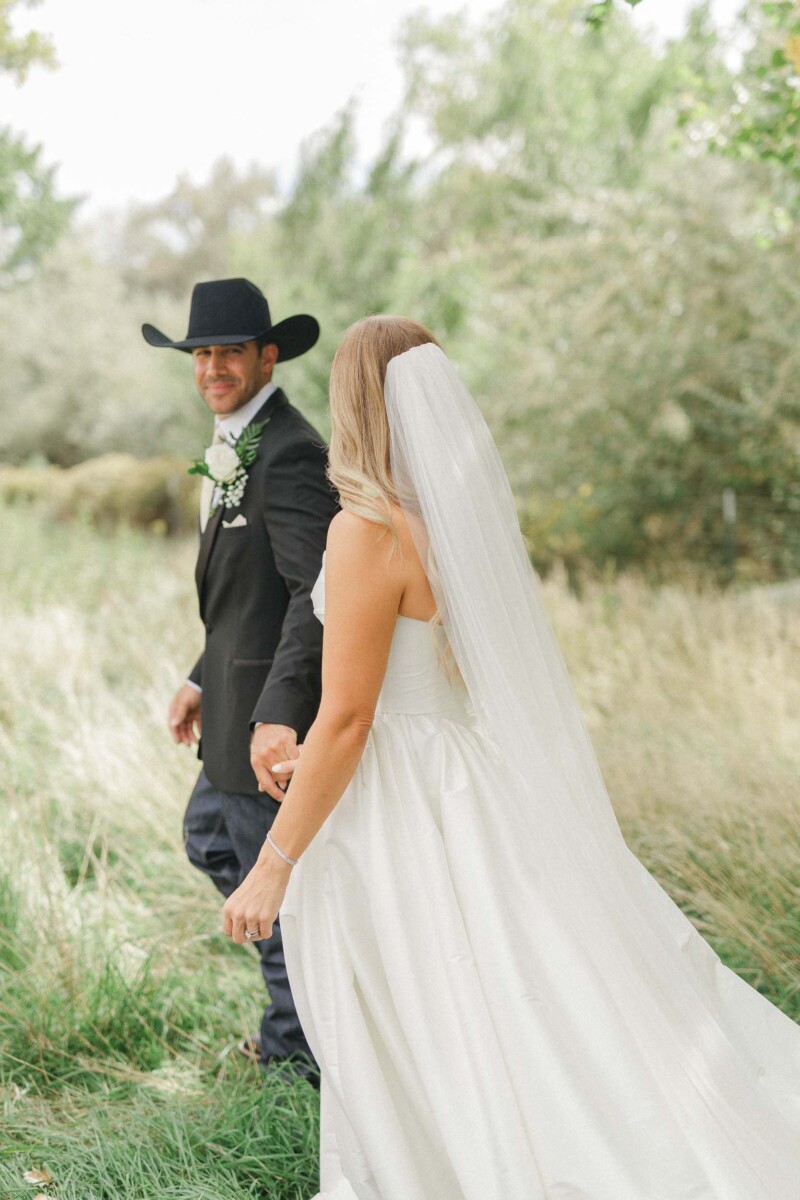 Bride and groom holding hands outdoors during rural Utah wedding.