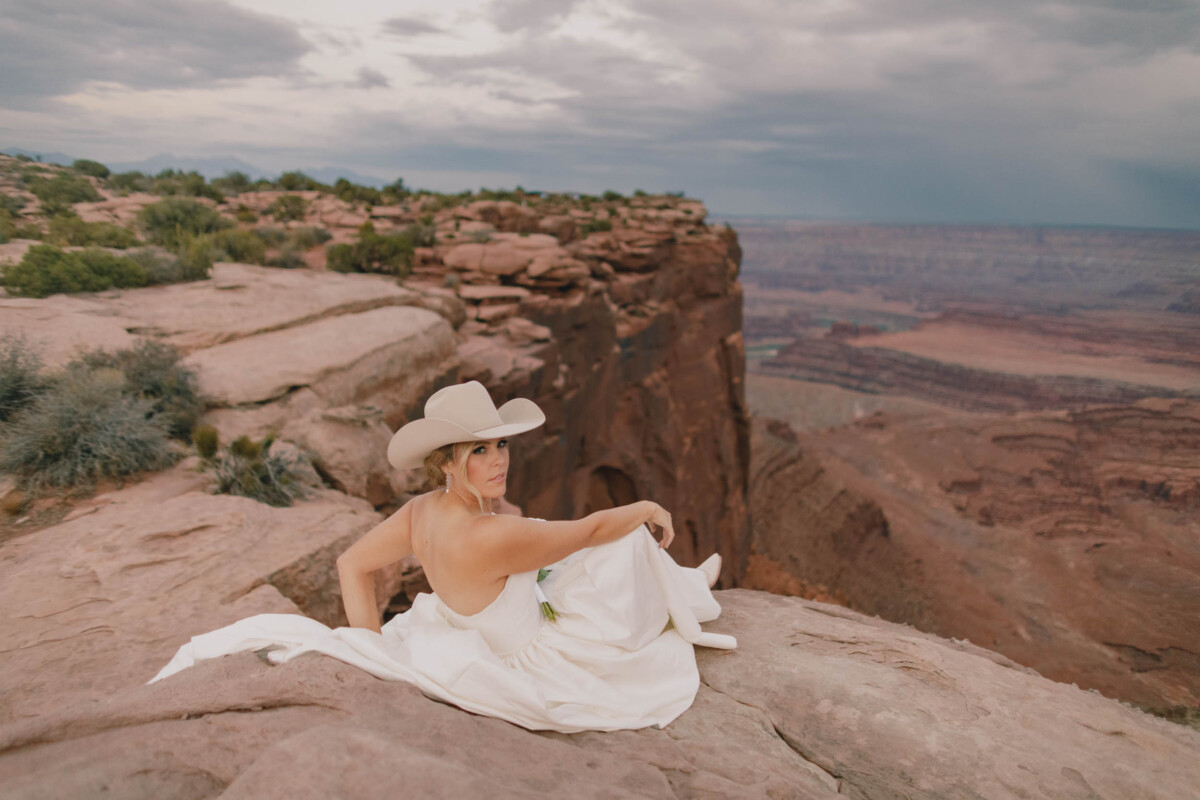 Bride sitting on rocks at Moab Utah canyon.