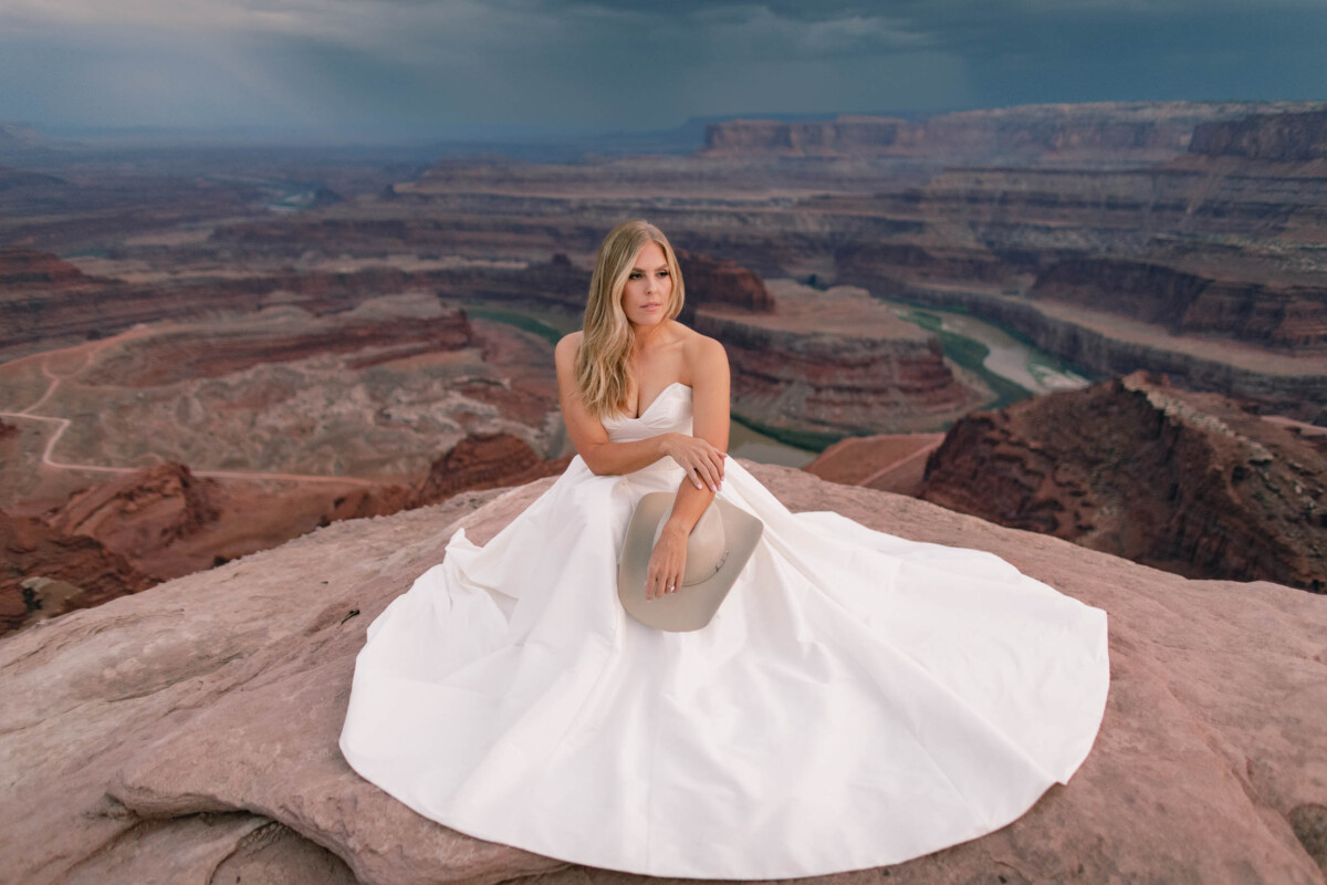 Elegant bride sitting on rock at Moab Utah canyon.