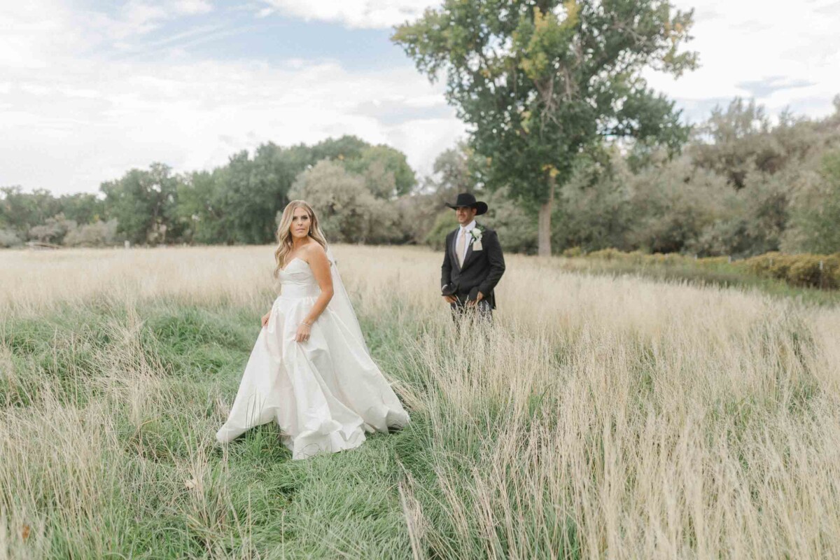Bride and groom standing in a grassy field during their fall wedding in Utah.