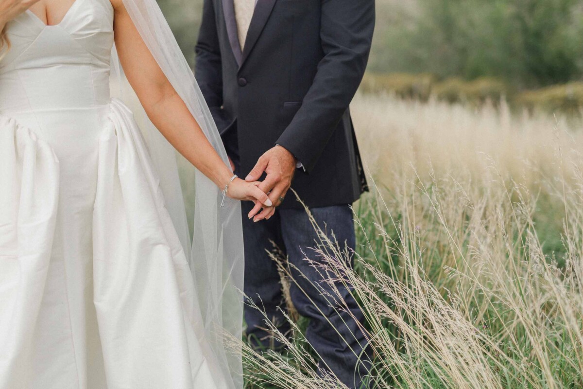 Bride and groom holding hands in a scenic outdoor setting.