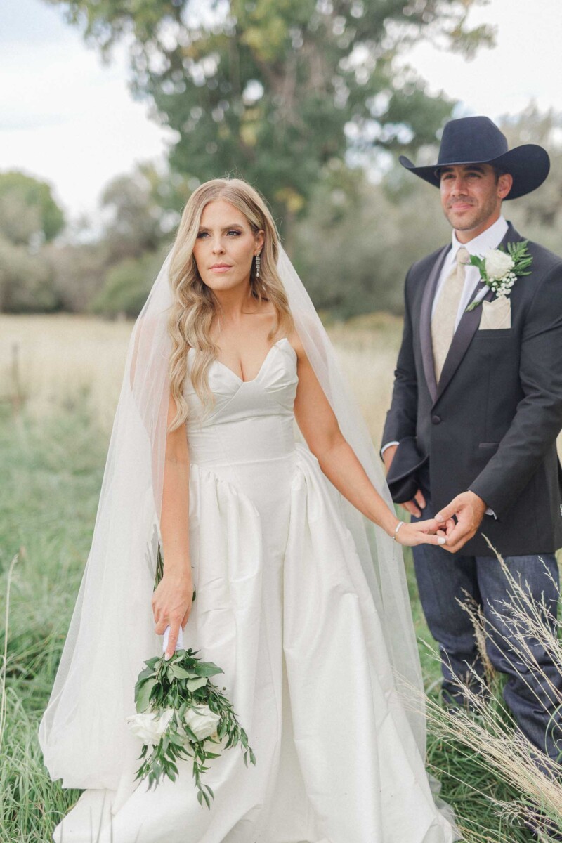 Bride and groom holding hands outdoors in a rural Utah setting.