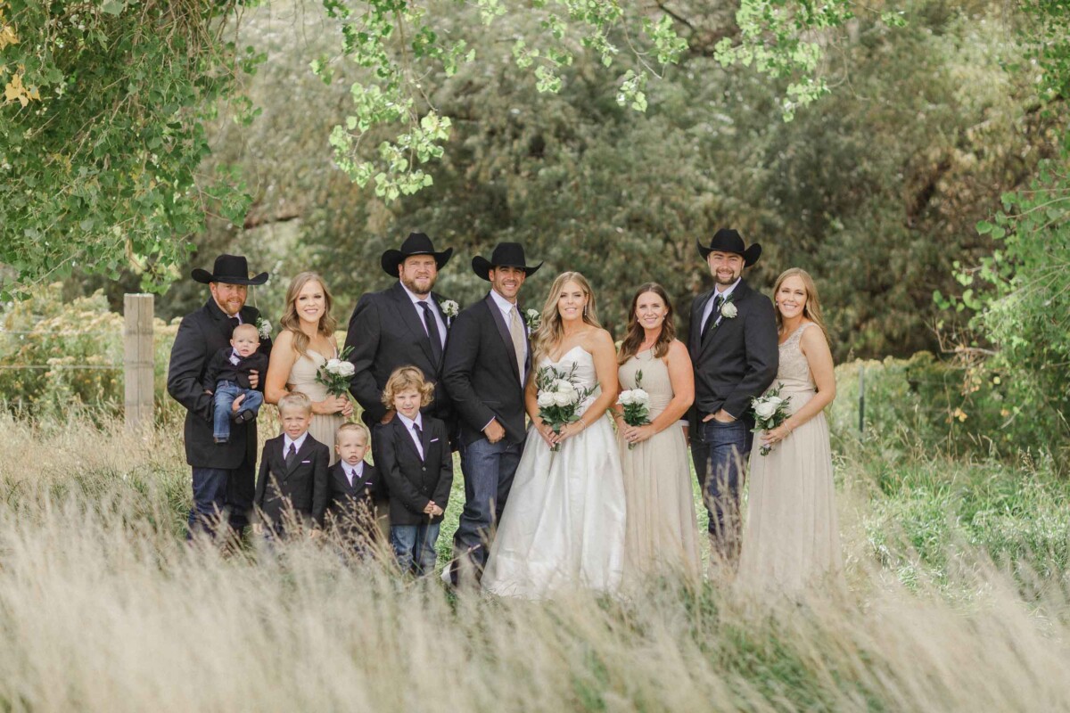 Beautiful wedding party outdoors in rural Utah with lush greenery and tall grass.