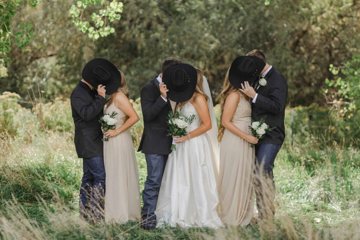 Elegant wedding photo of the bride, groom, and bridesmaids in a lush, green landscape.