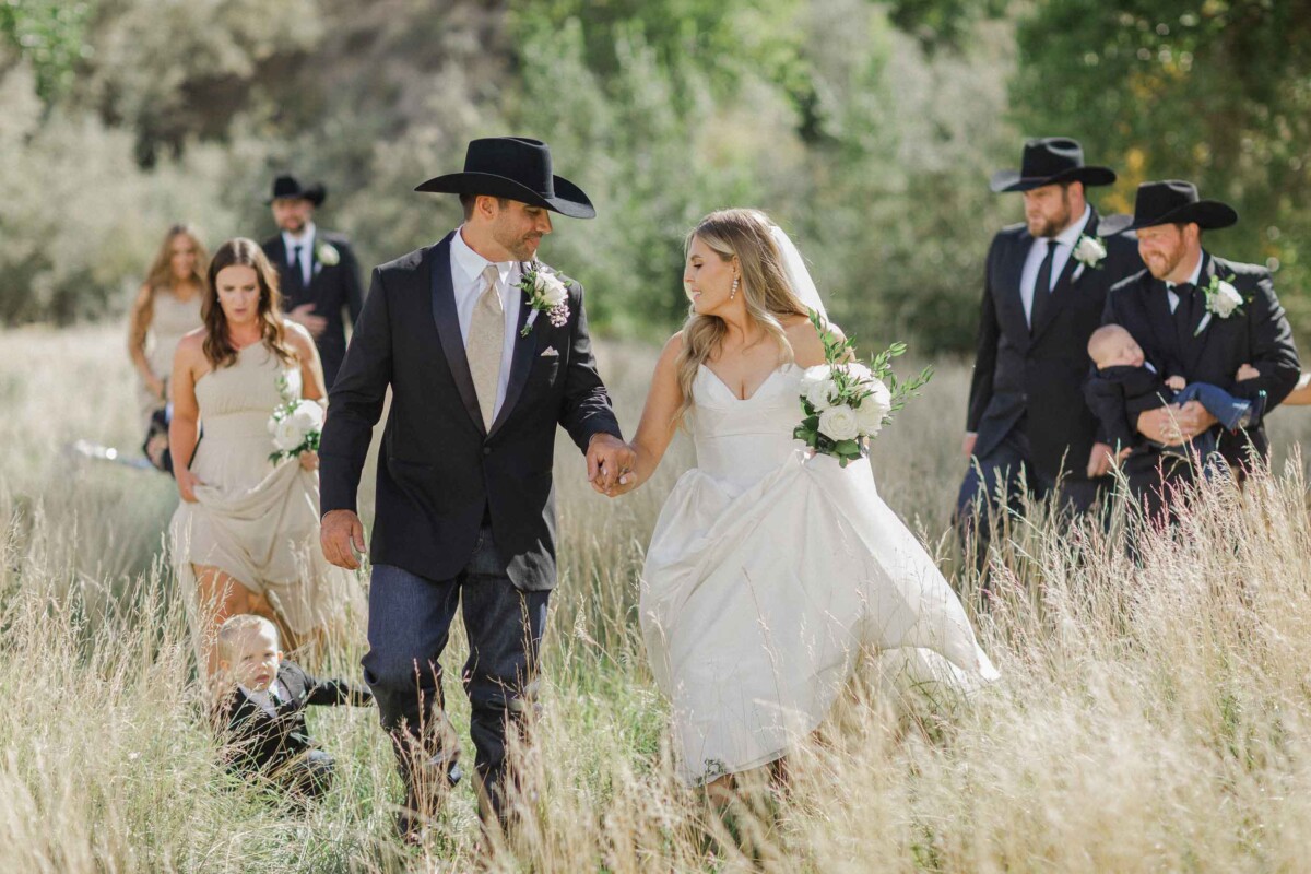 Bride and groom walking through a grassy field during their Utah fall wedding.