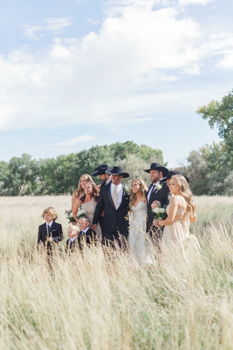 Wedding party standing in tall grass during a rural outdoor wedding.