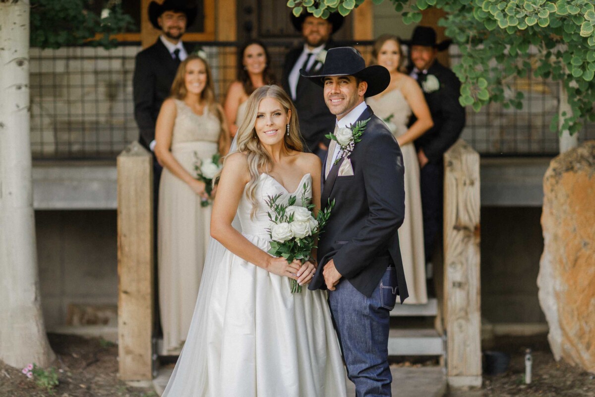 Bride and groom with wedding party in rustic outdoor setting.