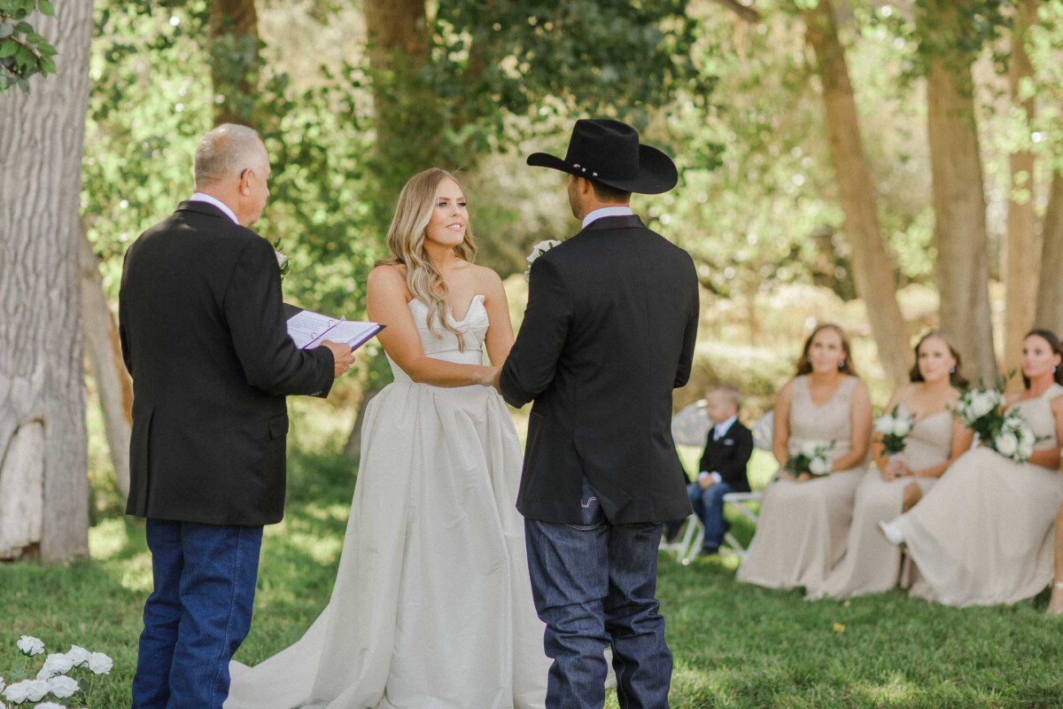 Wedding ceremony outdoors in a lush green forest with the bride and groom exchanging vows.