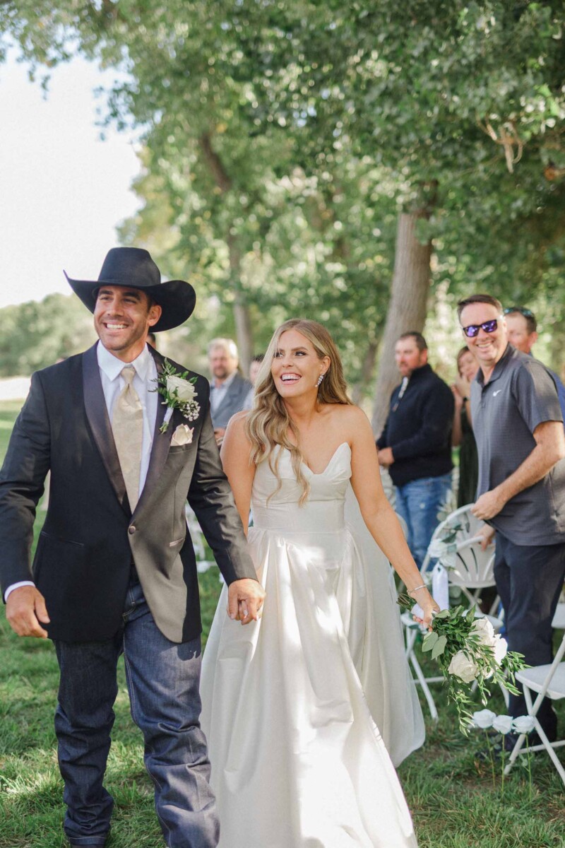Happy newlyweds Sean and Davie walking hand in hand after their Utah fall wedding.