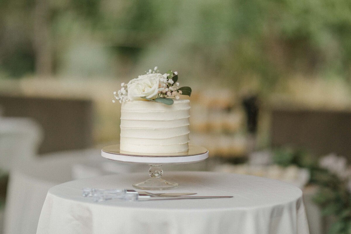 Wedding cake decorated with white roses and baby's breath on a rustic table.