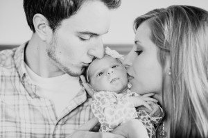 parents kissing newborn baby photo