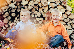 two little boys playing in fall leaves