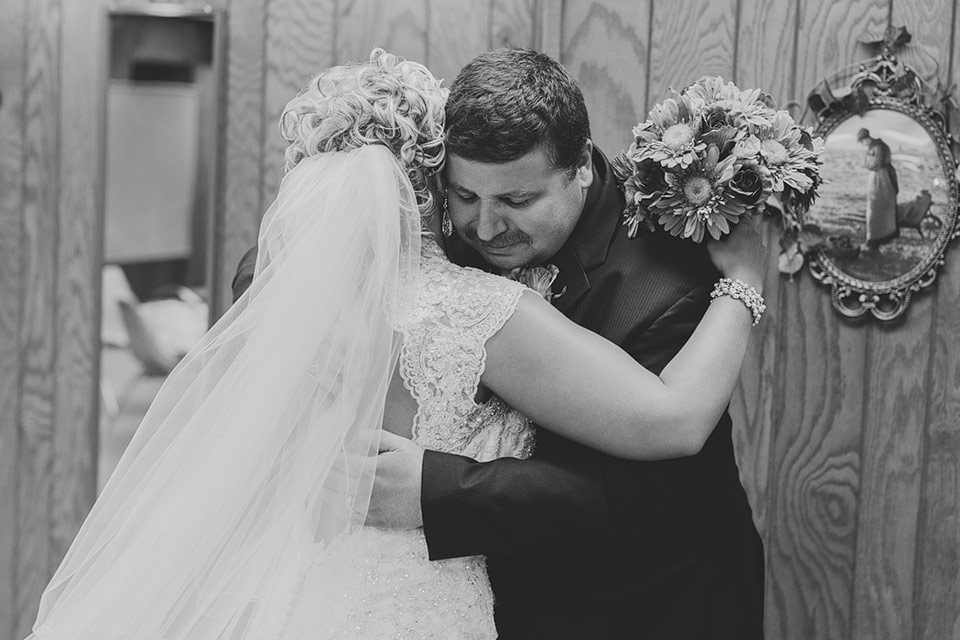 father hugging bride at wedding
