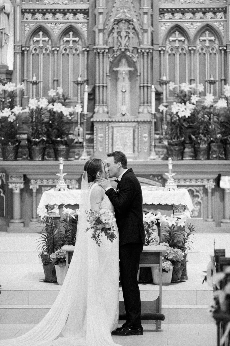 Church Wedding In St. Andrew’s Church, 714 E Walworth Ave, Delavan, WI black and white kissing at the alter