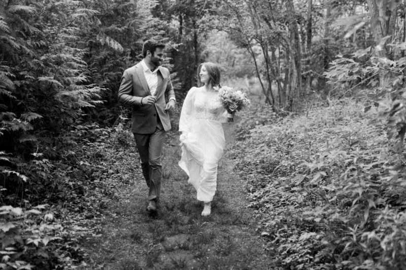 Bride and groom walking through forest in Milwaukee during Midwest photography shoot.