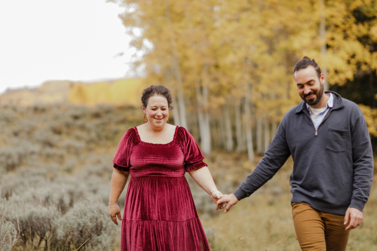 Wedding couple walking hand in hand in a scenic outdoor setting during fall.