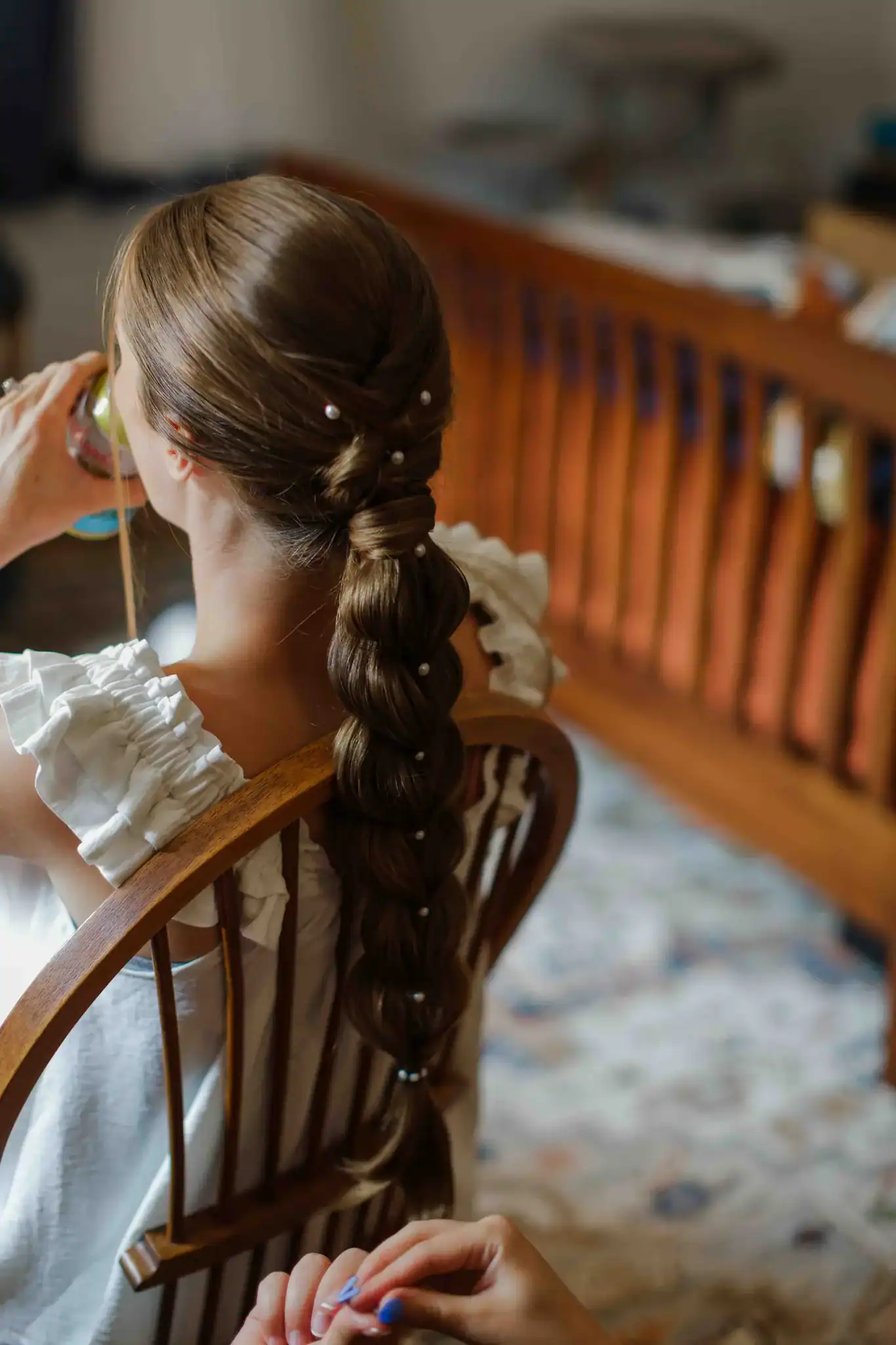 Bride with pearl braided updo getting hair done before backyard wedding ceremony in Wisconsin Dells
