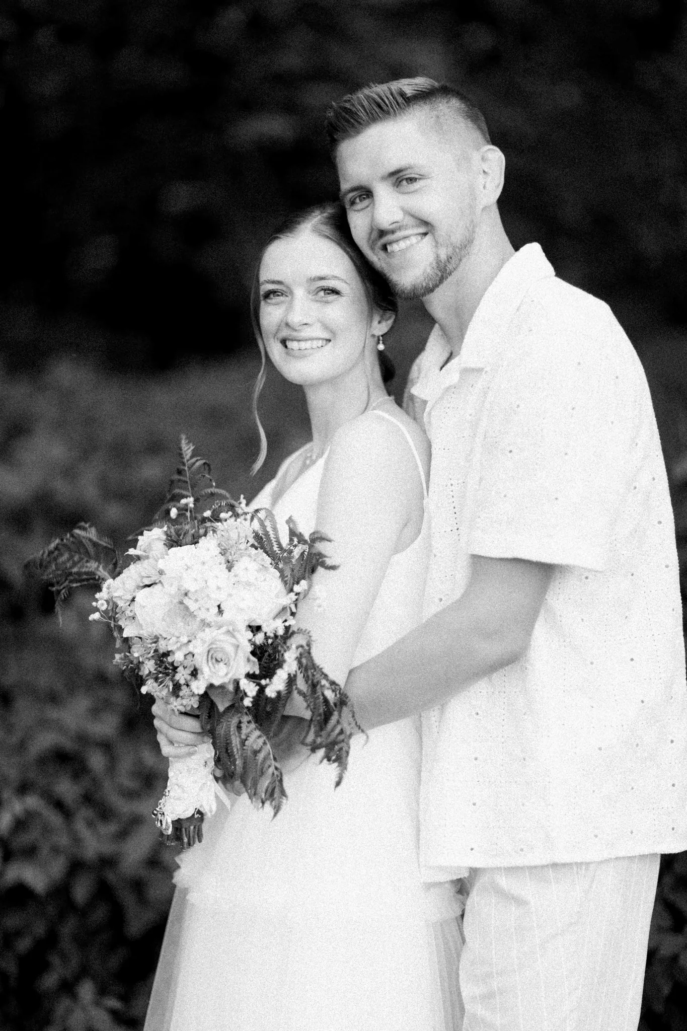 Black and white portrait of bride and groom with floral bouquet at Wisconsin Dells backyard wedding