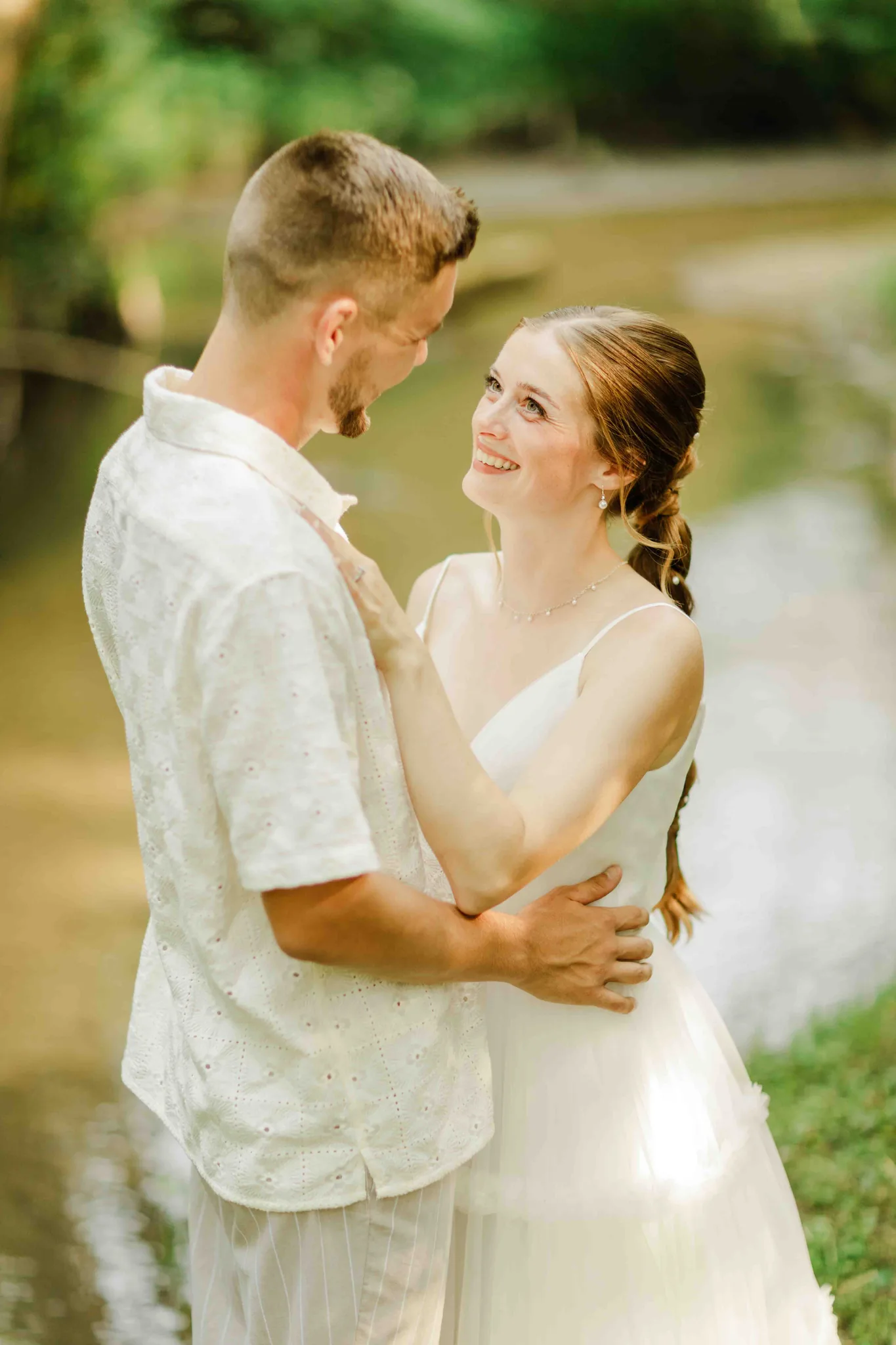 Bride laughing and looking up at groom during couple portraits by creek at Wisconsin Dells wedding