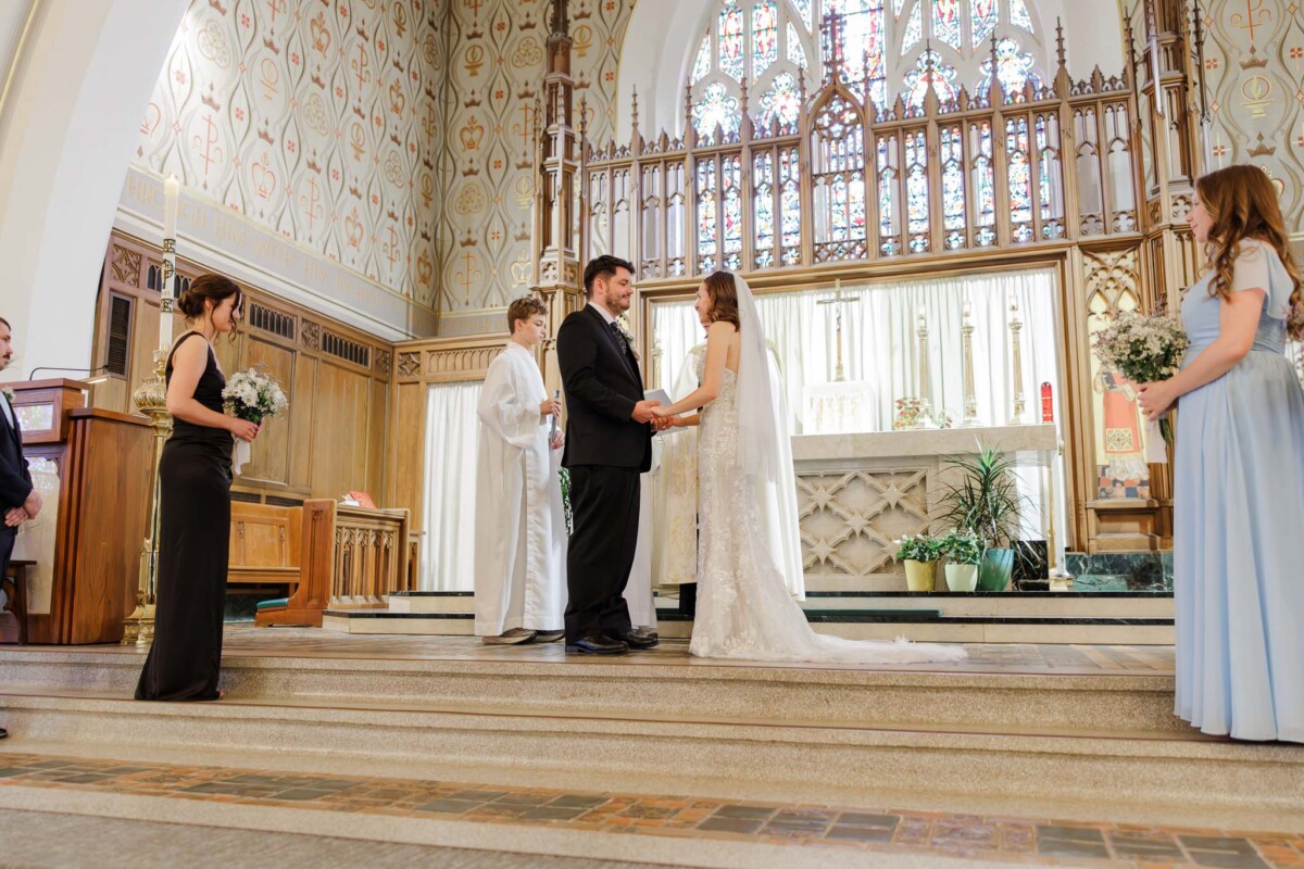 Wide ceremony view of bride and groom at the altar inside St. Stephen Cathedral