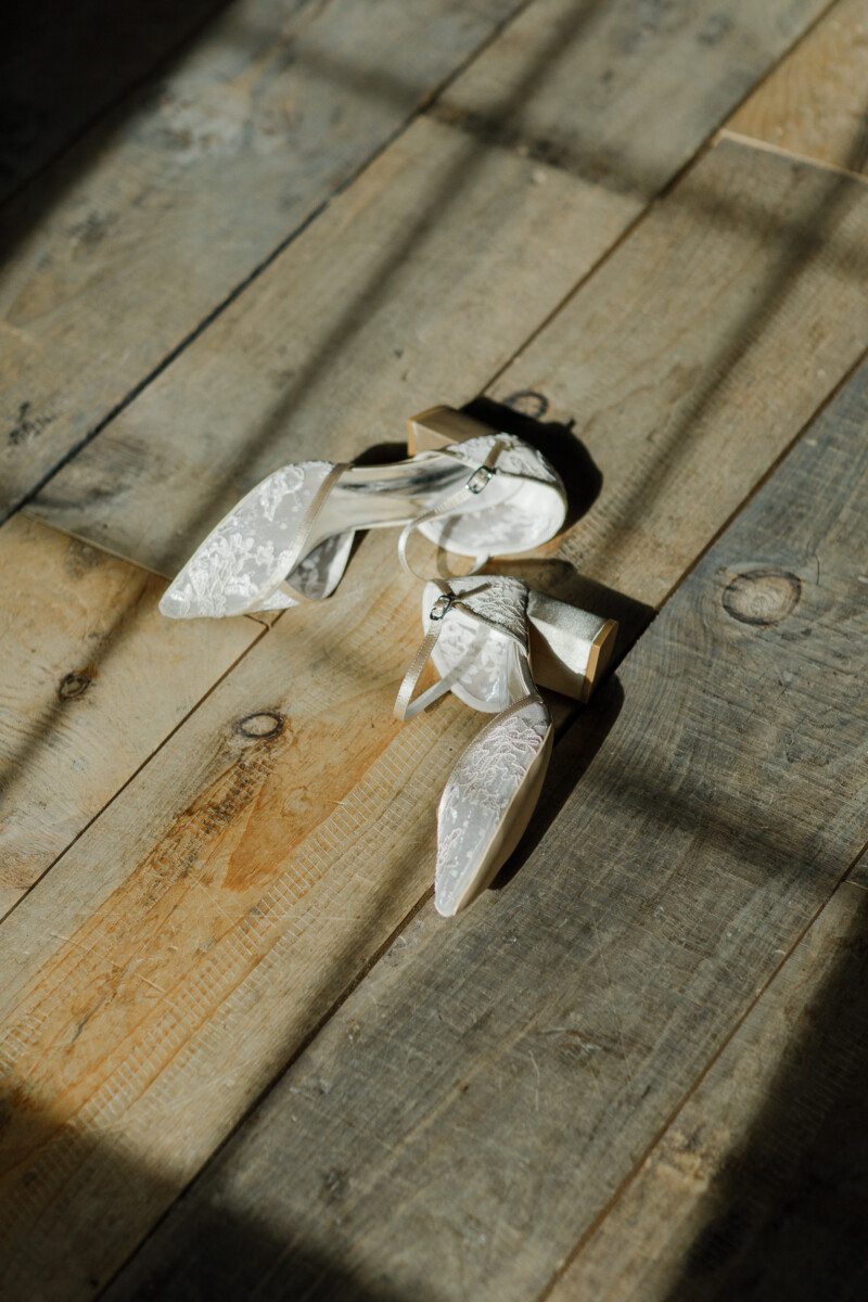 Lace block-heel bridal shoes on weathered barn floorboards in afternoon light