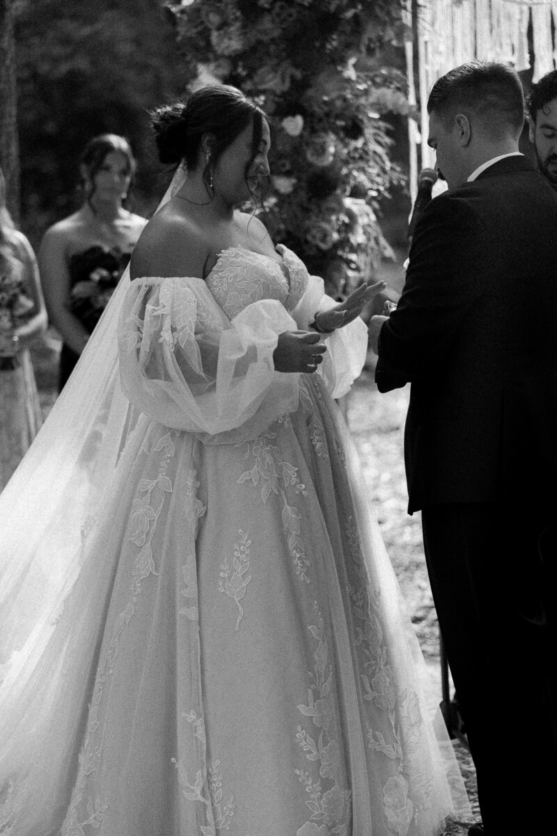 Black and white photo of the bride and groom holding hands at the altar