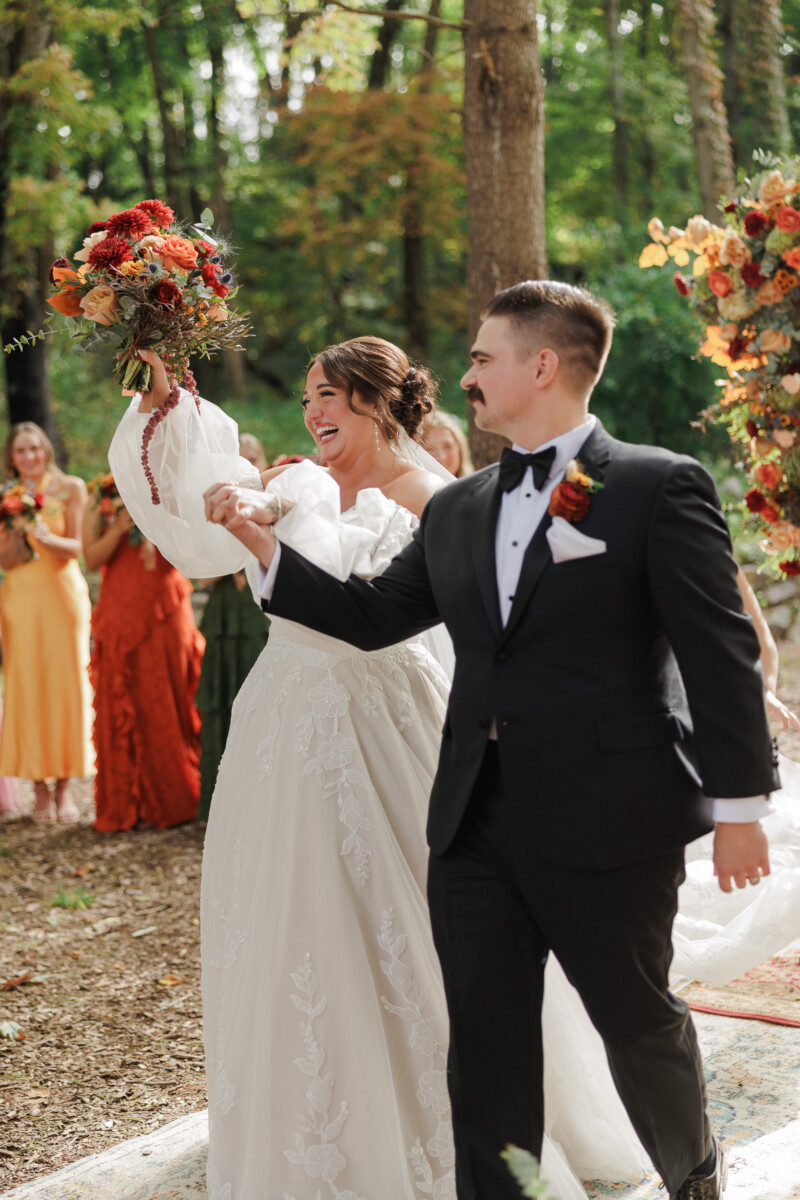 Bride raising her bouquet beside the groom as they are announced married