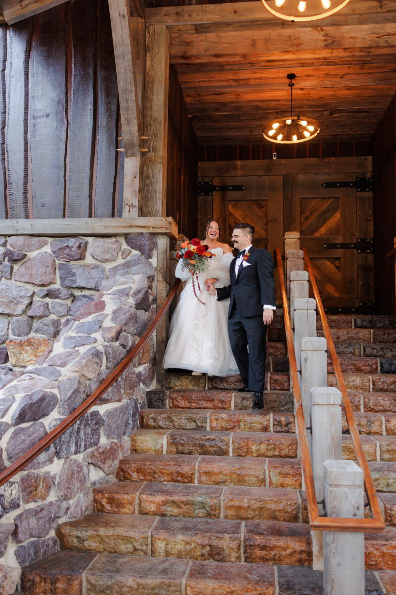 Bride and groom on the stone staircase beneath the barn's lantern-lit entry