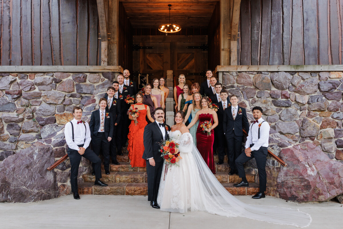 Full wedding party on the stone steps of the barn entrance