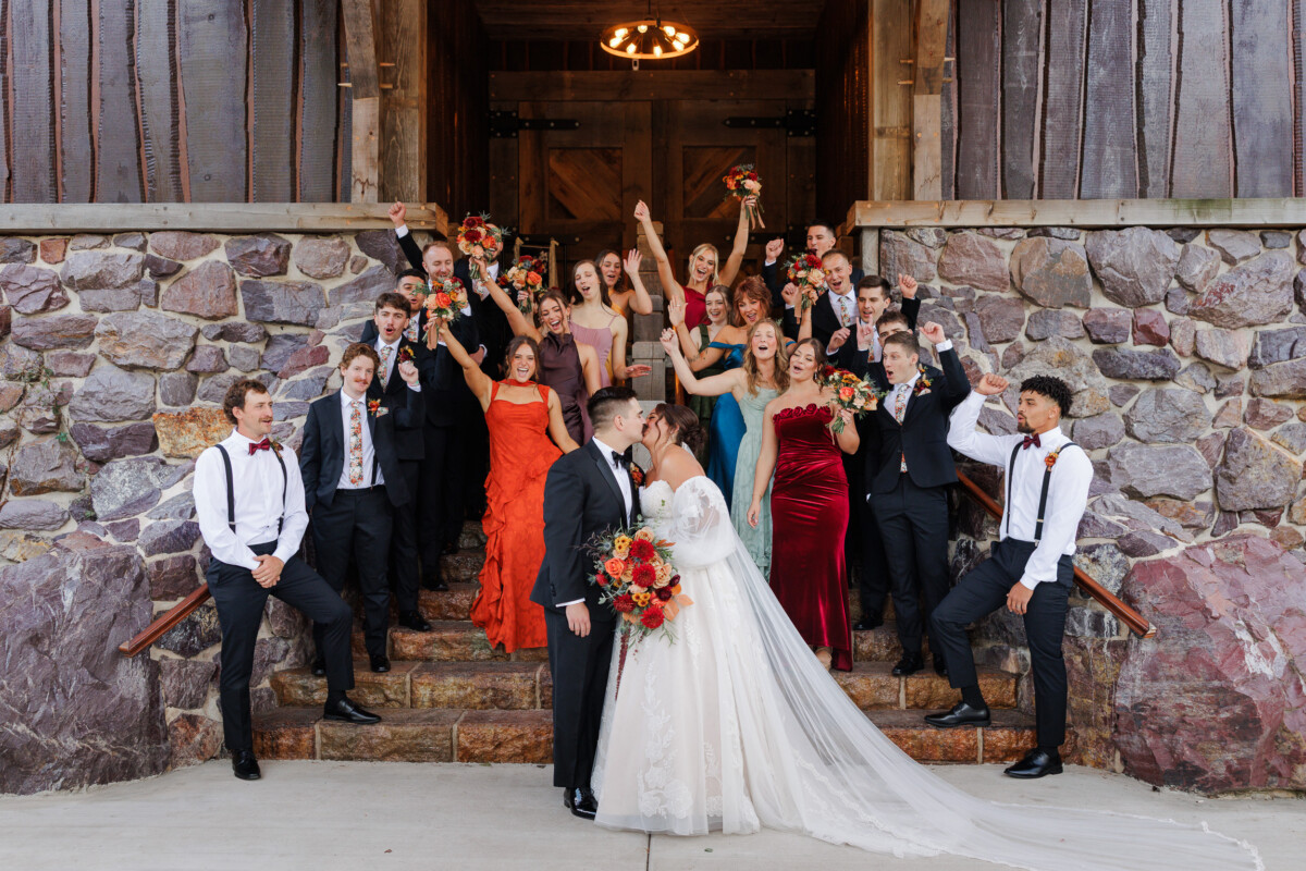 Wedding party cheering with arms raised on the stone steps