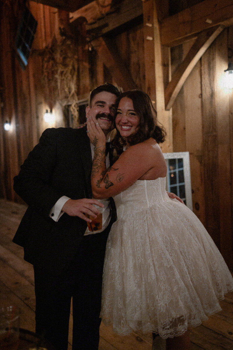 Groom and bride embracing in the barn during the evening reception